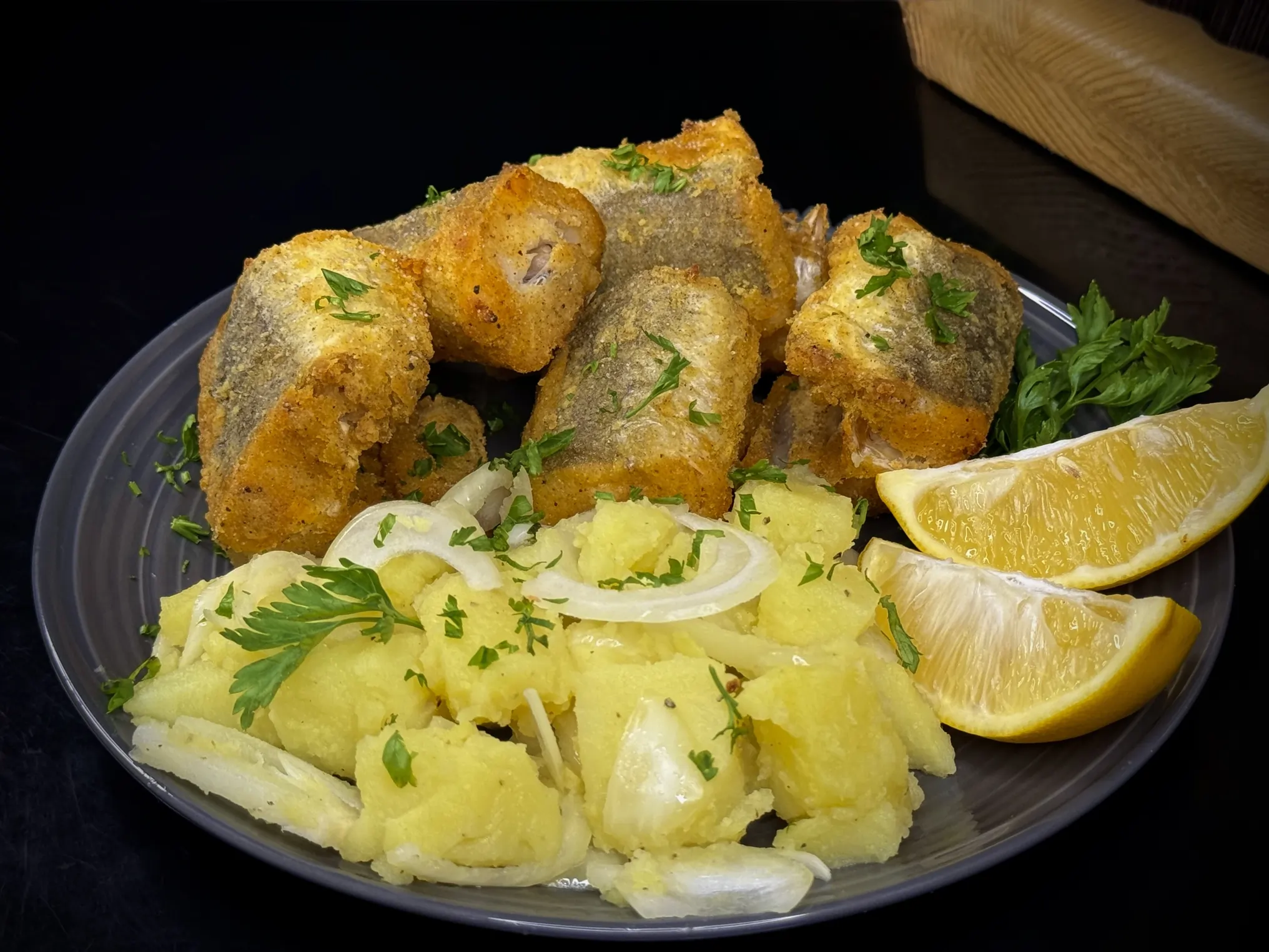 oslic-iz-rerne-krompir-salata Zlatno pečeni oslić iz rerne sa kukuruznim brašnom, serviran sa krompir salatom i kriškom limuna, savršen za posno jelo.