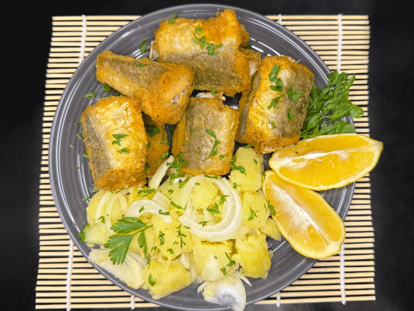 Zlatno pečeni oslić iz rerne sa kukuruznim brašnom, serviran sa krompir salatom i kriškom limuna, savršen za posno jelo.