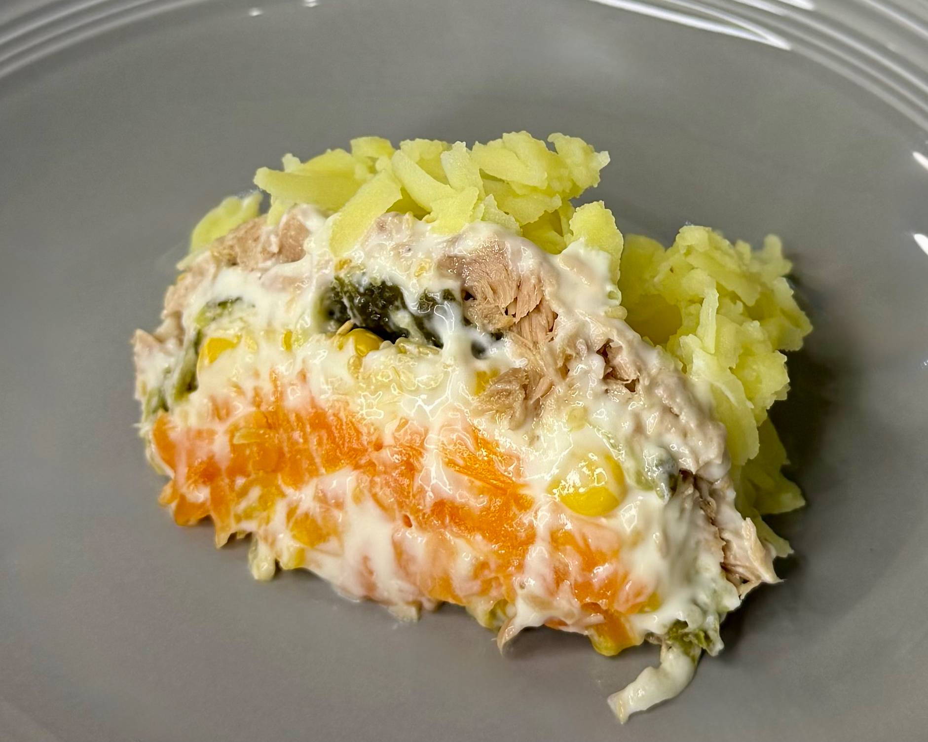 Posna salata - servirana na tanjiru, prikaz slojeva mrkve, tunjevine, krompira i posne majoneze.