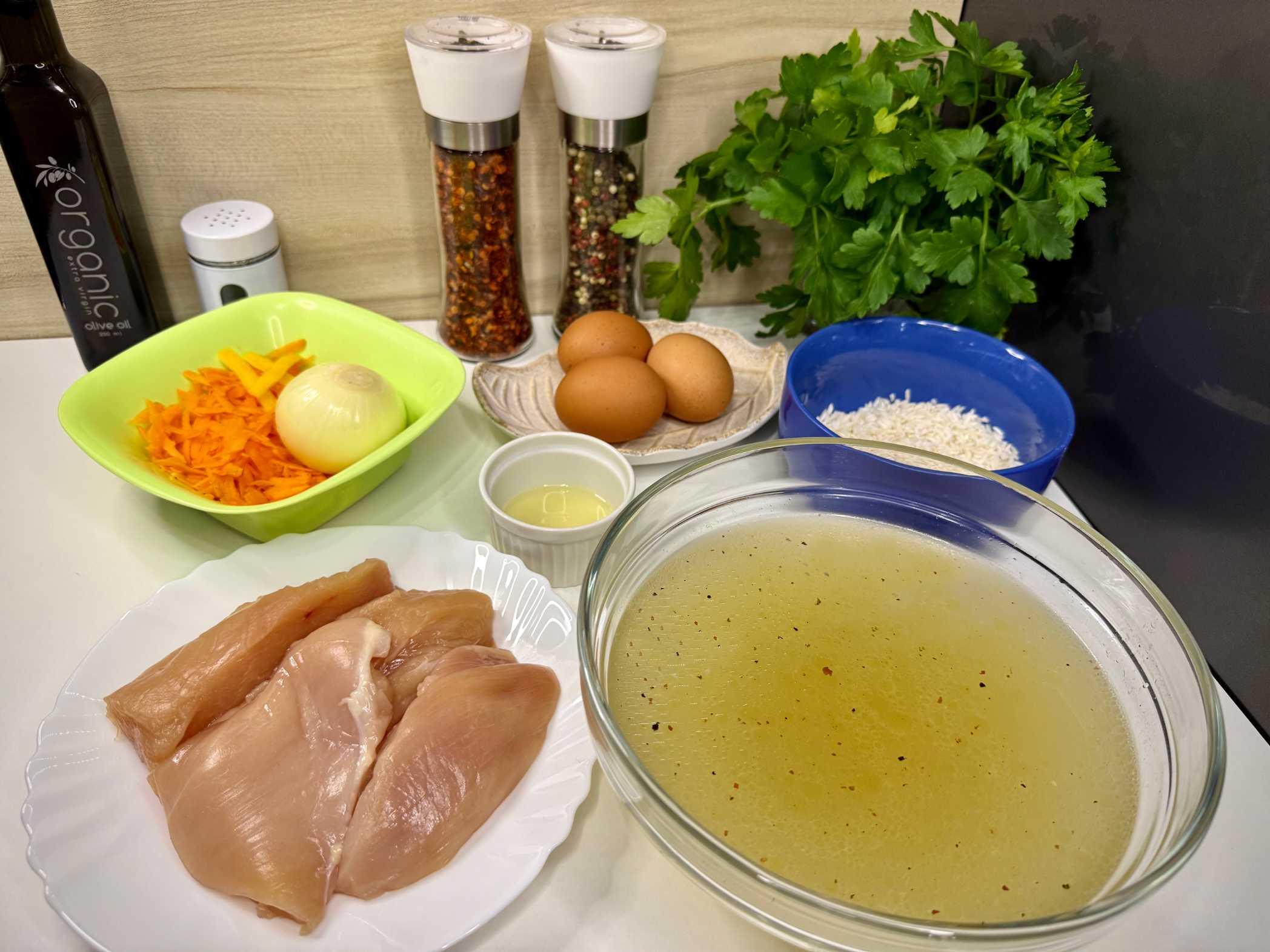 Sastojci za avgolemono supu: pileća prsa, pileći temeljac, mrkva, jaja, limun, riža na radnoj površini.