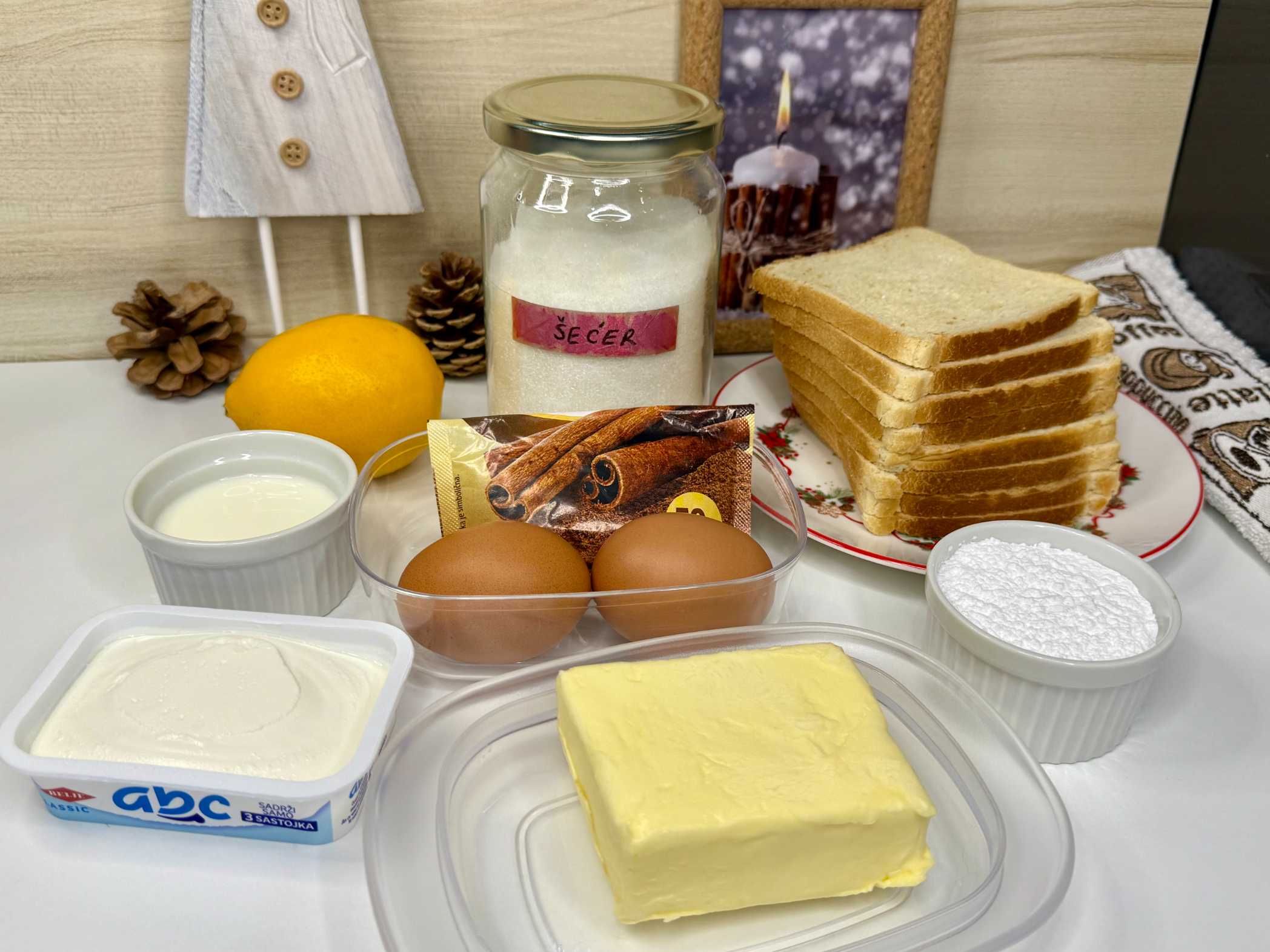 Sastojci za francuski tost poredani na dasci: tost hljeb, maslac, jaja, mlijeko, šećer, cimet, limun, krem sir.